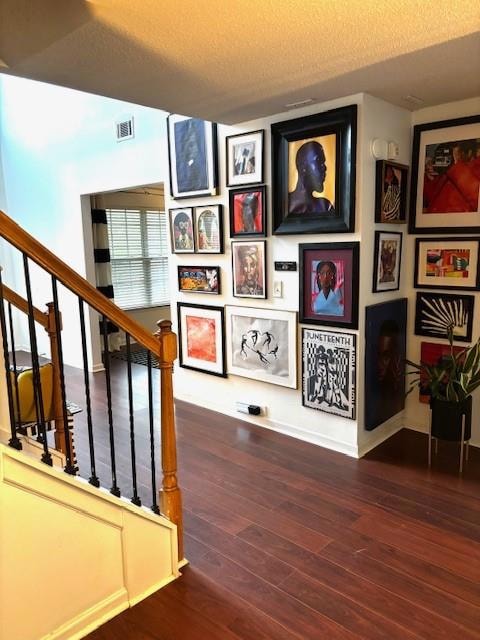 Stairway with hardwood / wood-style flooring and a textured ceiling