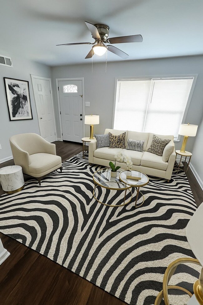 Living room featuring plenty of natural light, wood finished floors, a ceiling fan, and baseboards