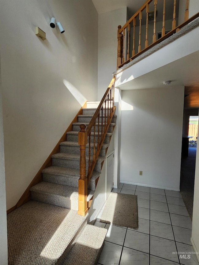 Stairs featuring a high ceiling and tile patterned flooring