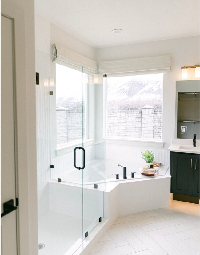 Bathroom featuring vanity, healthy amount of natural light, a bath, and light tile patterned flooring