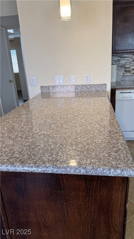 Kitchen view of a peninsula, dishwasher, and dark stone counters