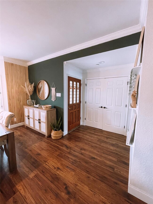 Foyer featuring ornamental molding and dark hardwo