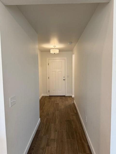 Hallway featuring baseboards and dark wood finished floors