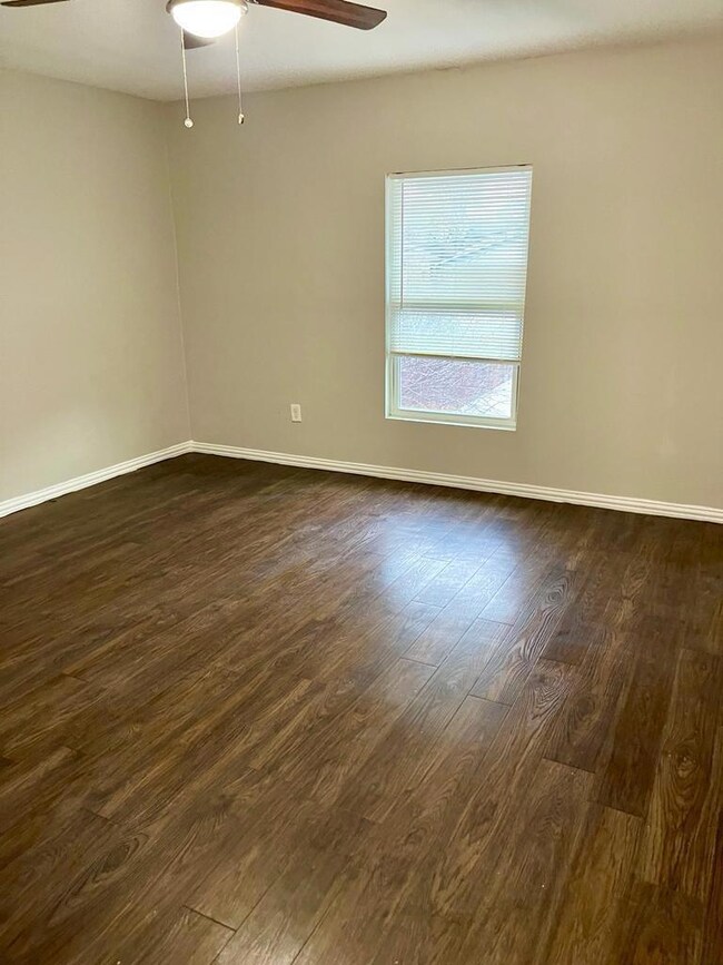 Empty room with a ceiling fan, dark wood finished 