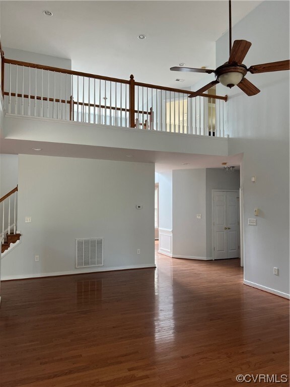 Hardwood floored spare room with a high ceiling and ceiling fan