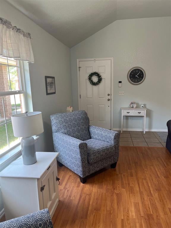 Sitting room featuring vaulted ceiling, light wood finished floors, and baseboards