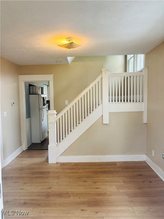 Stairway featuring a textured ceiling and hardwood / wood-style flooring
