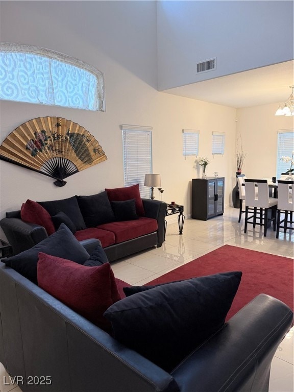 Living room featuring light tile patterned floors, a chandelier, and a towering ceiling
