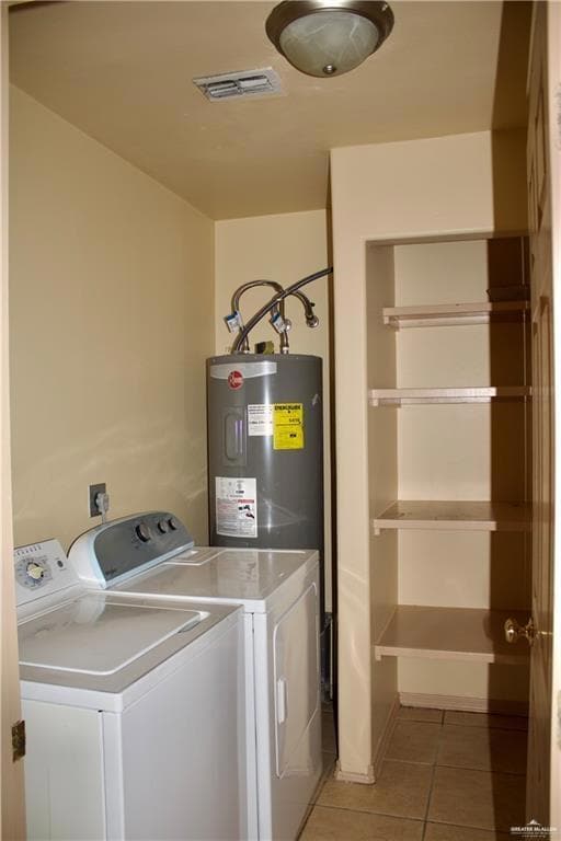 Laundry area featuring water heater, separate washer and dryer, and light tile patterned floors