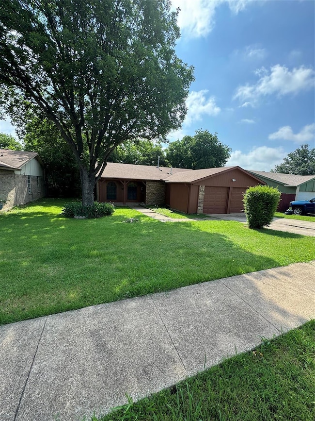 Ranch-style home featuring a front yard and a gara
