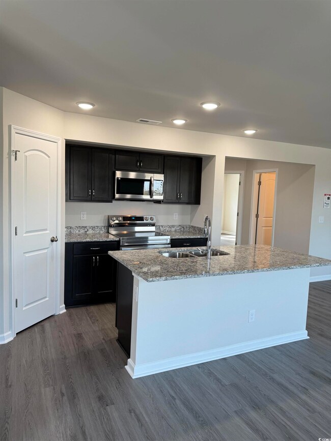 Kitchen featuring dark cabinetry, dark wood-type f
