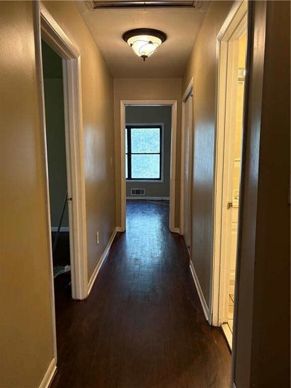 Corridor featuring dark wood-type flooring and baseboards