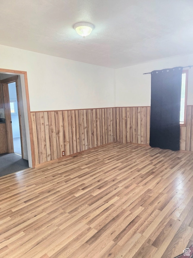 Empty room featuring wood finished floors, wainscoting, and wooden walls