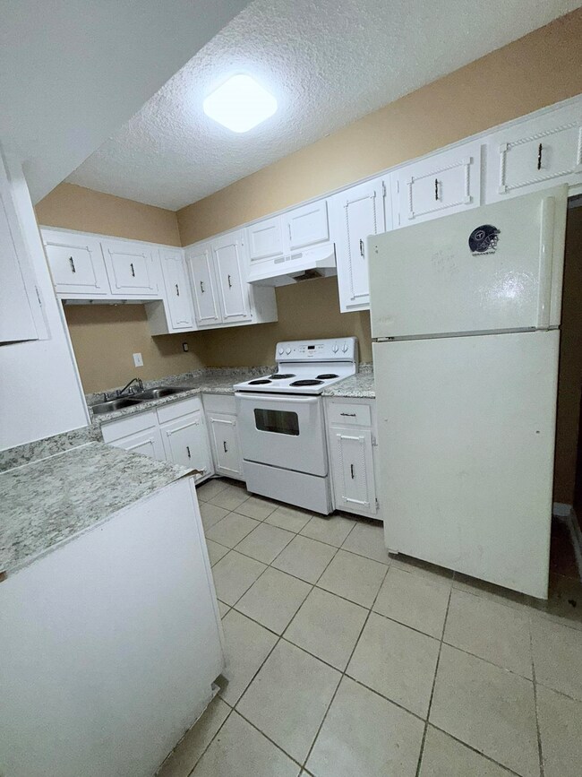 Kitchen with white appliances, light tile patterne