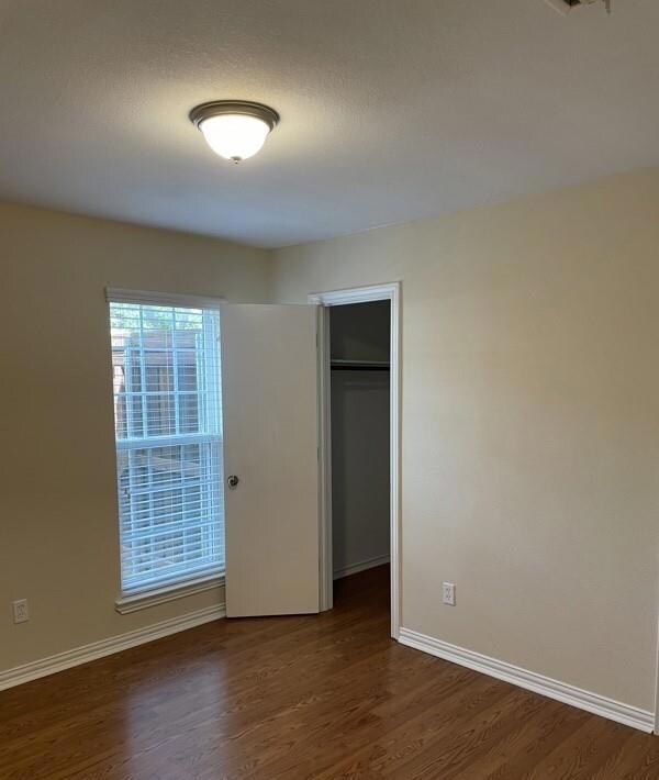 Unfurnished bedroom with a closet and dark hardwoo