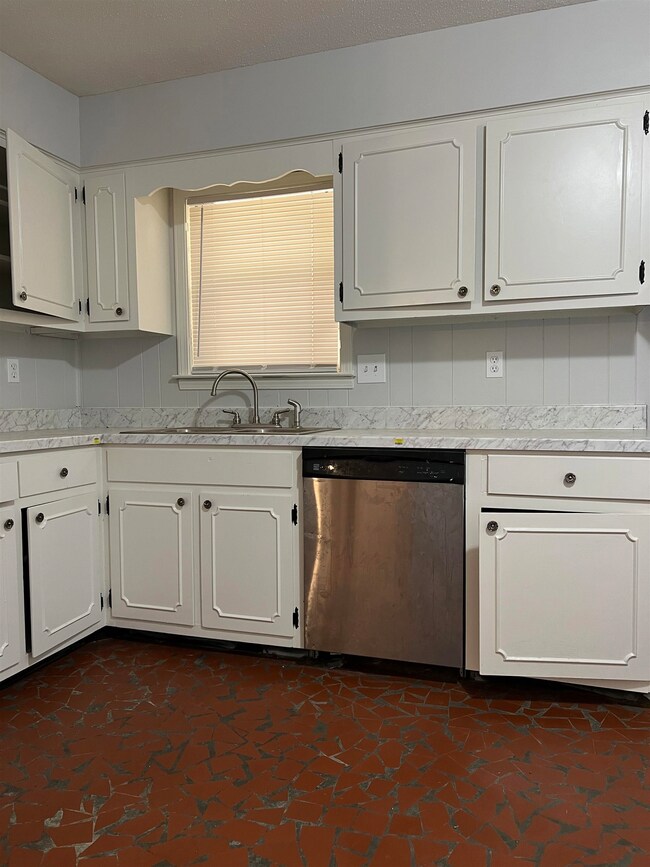 Kitchen featuring sink, dishwasher, and white cabi