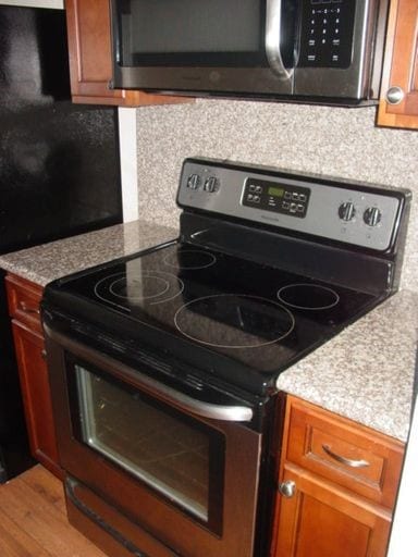 Kitchen featuring appliances with stainless steel finishes, brown cabinets, light wood finished floors, and decorative backsplash