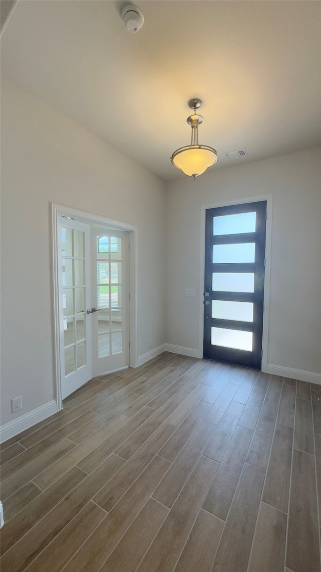 Empty room featuring a smoke detector, dark wood-style flooring, and french doors