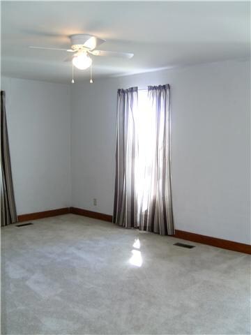 Large living room has carpet with original hardwood floors underneath