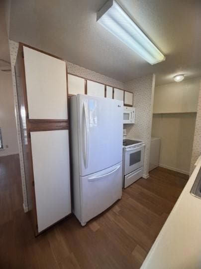 Kitchen featuring white cabinetry, white applianc