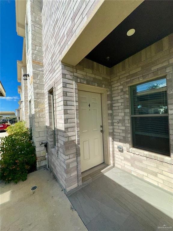 Doorway to property featuring stone siding and a patio area