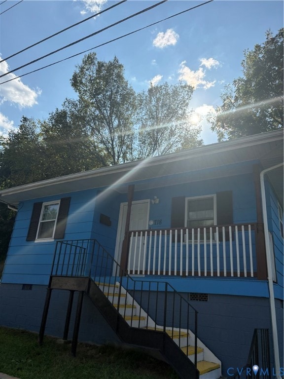 View of front facade with stairway, crawl space, and a porch