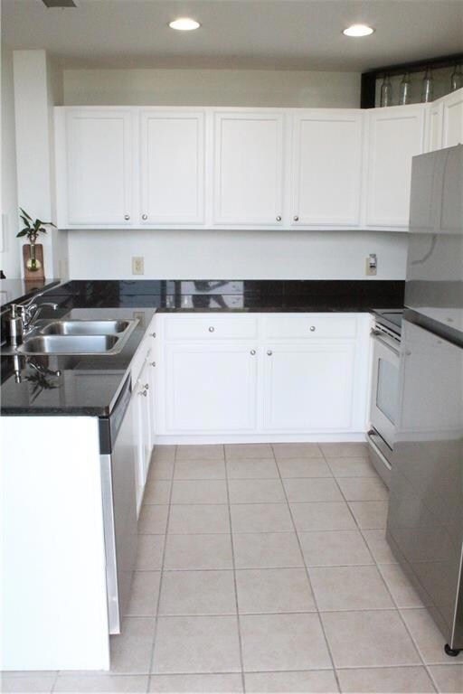 Kitchen with a sink, light tile patterned floors, white cabinetry, stove, and recessed lighting