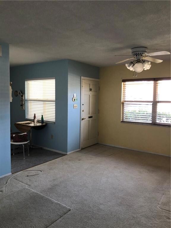 The living room looking back to the front door and kitchen. The carpet is newer and the photo makes it look dirtier.