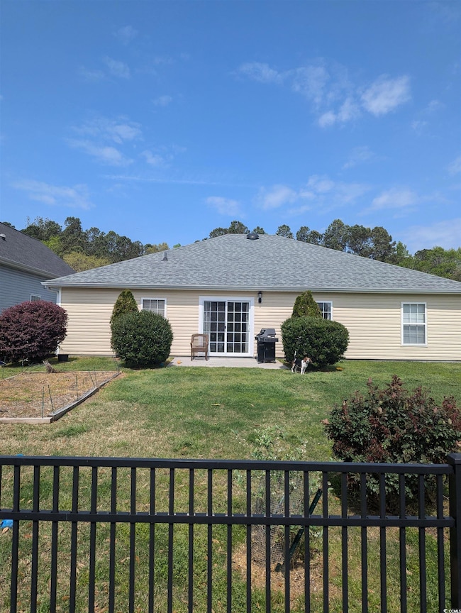 Back of property with a shingled roof, fence, and 