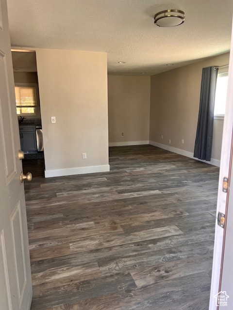 Unfurnished room featuring a textured ceiling and dark wood-type flooring
