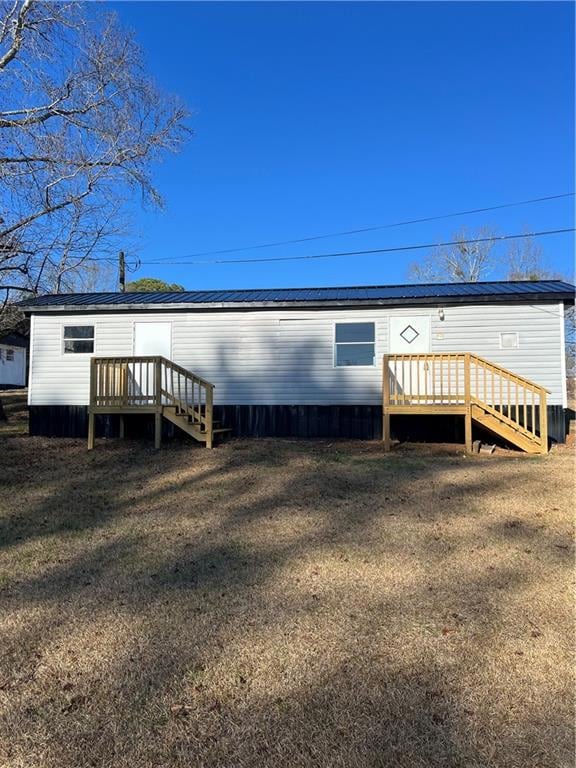 Rear view of house with a yard, metal roof, and a 