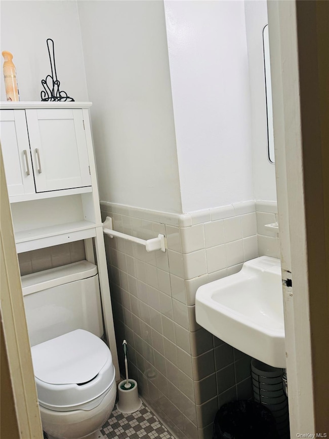 Bathroom featuring tile walls, tile patterned flooring, and a wainscoted wall