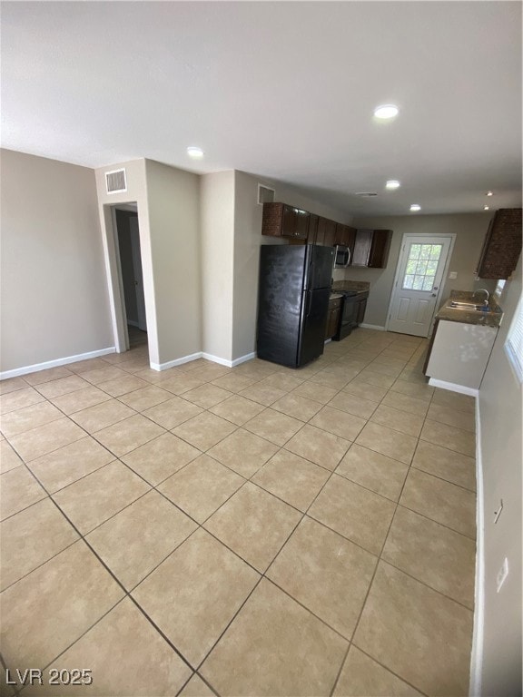 Kitchen featuring refrigerator, light tile patterned floors, recessed lighting, dark brown cabinets, and range