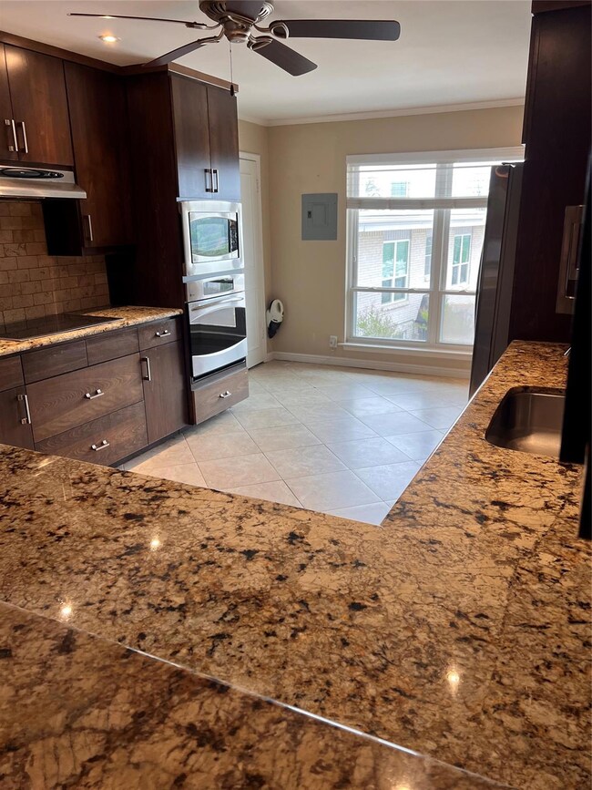 Kitchen with light tile flooring, ceiling fan, wal