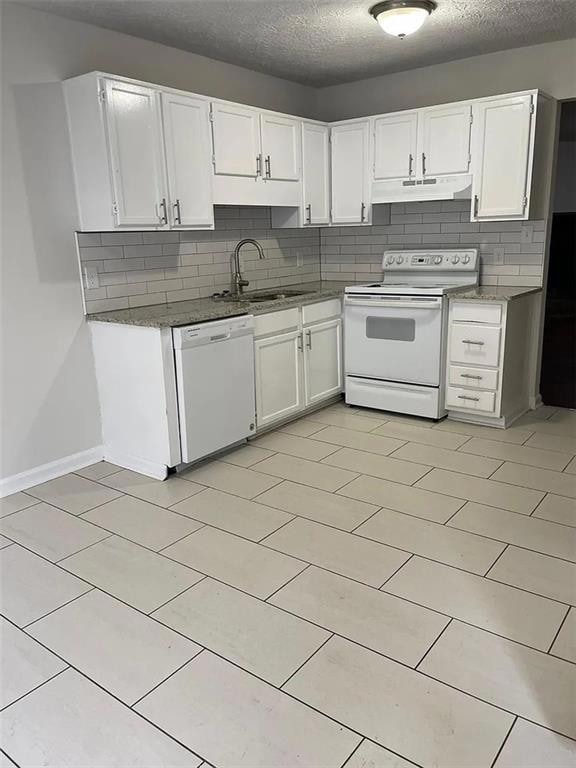 Kitchen with white appliances, under cabinet range hood, a sink, tasteful backsplash, and white cabinetry