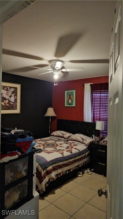 Tiled bedroom featuring ceiling fan