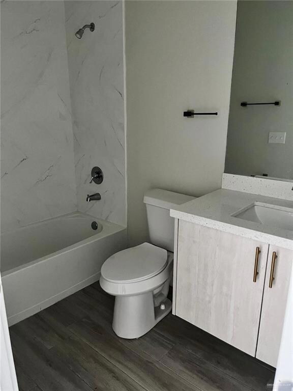Full bath with vanity, dark wood-style flooring, and shower / bath combination