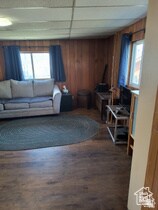 Living area with plenty of natural light, wood walls, dark wood-style floors, and a paneled ceiling