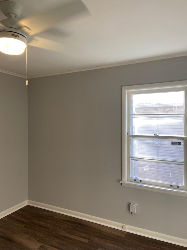 Unfurnished room with crown molding, baseboards, and dark wood finished floors