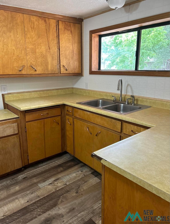 Kitchen featuring light countertops, brown cabinets, dark wood-type flooring, and a textured ceiling
