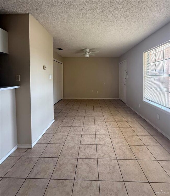 Unfurnished room featuring a ceiling fan, a textured ceiling, and light tile patterned floors