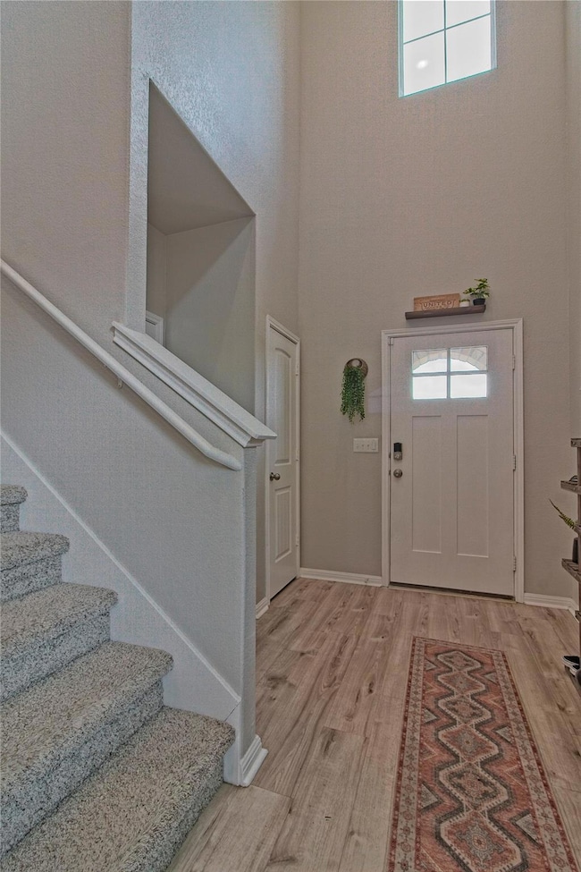 Entryway with stairs, a towering ceiling, and woo