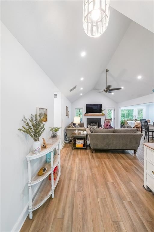 Living area with light wood-type flooring, healthy amount of natural light, a ceiling fan, recessed lighting, and high vaulted ceiling