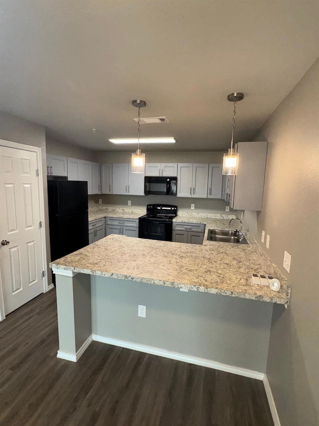 Kitchen with black / electric stove, a sink, baseb