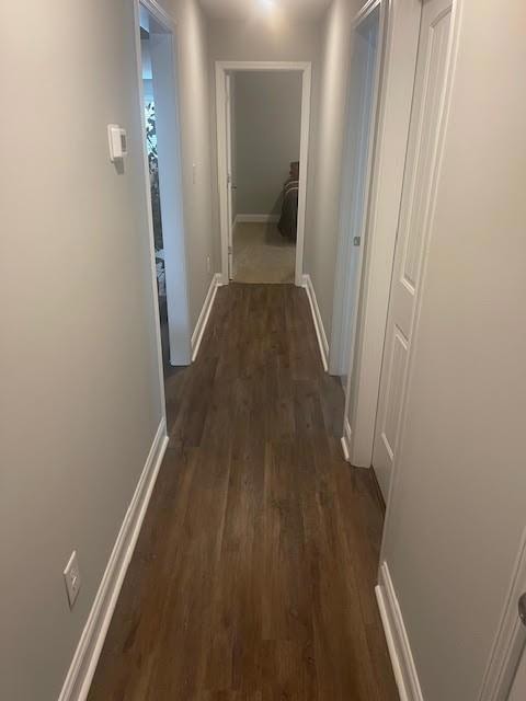 Hallway featuring dark wood-style flooring and bas