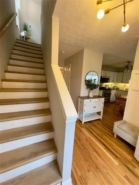 Staircase with wood finished floors and a textured ceiling