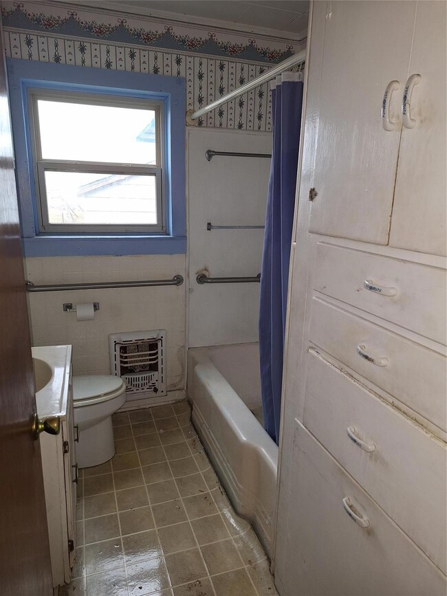 Full bathroom featuring vanity, toilet, heating un