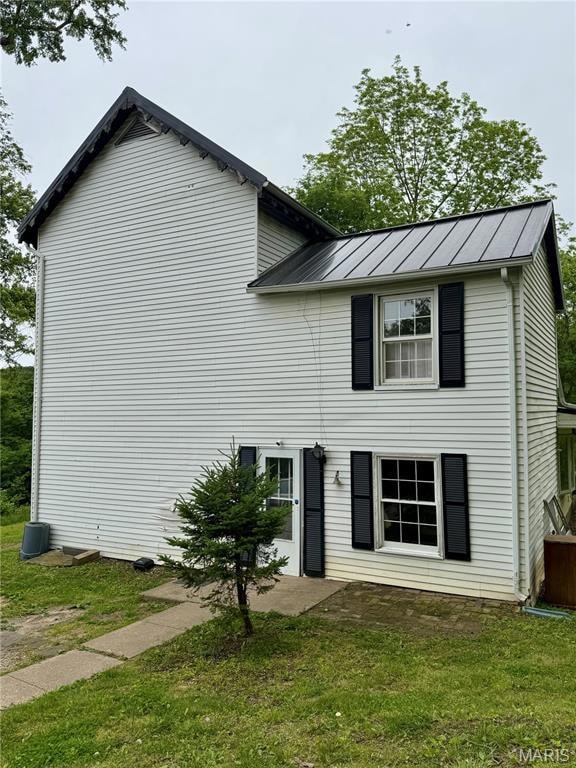 View of front of house with a standing seam roof, metal roof, and a front yard