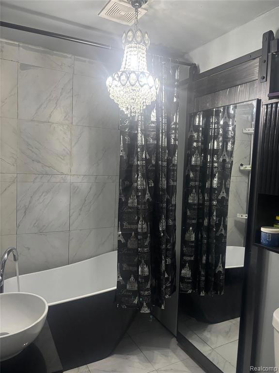 Full bathroom with a freestanding tub and a chandelier