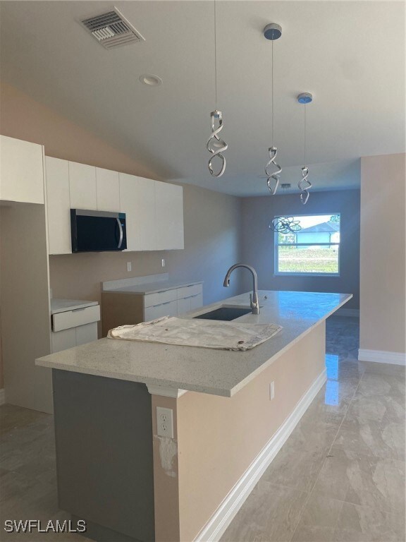 Kitchen with visible vents, white cabinets, a sink